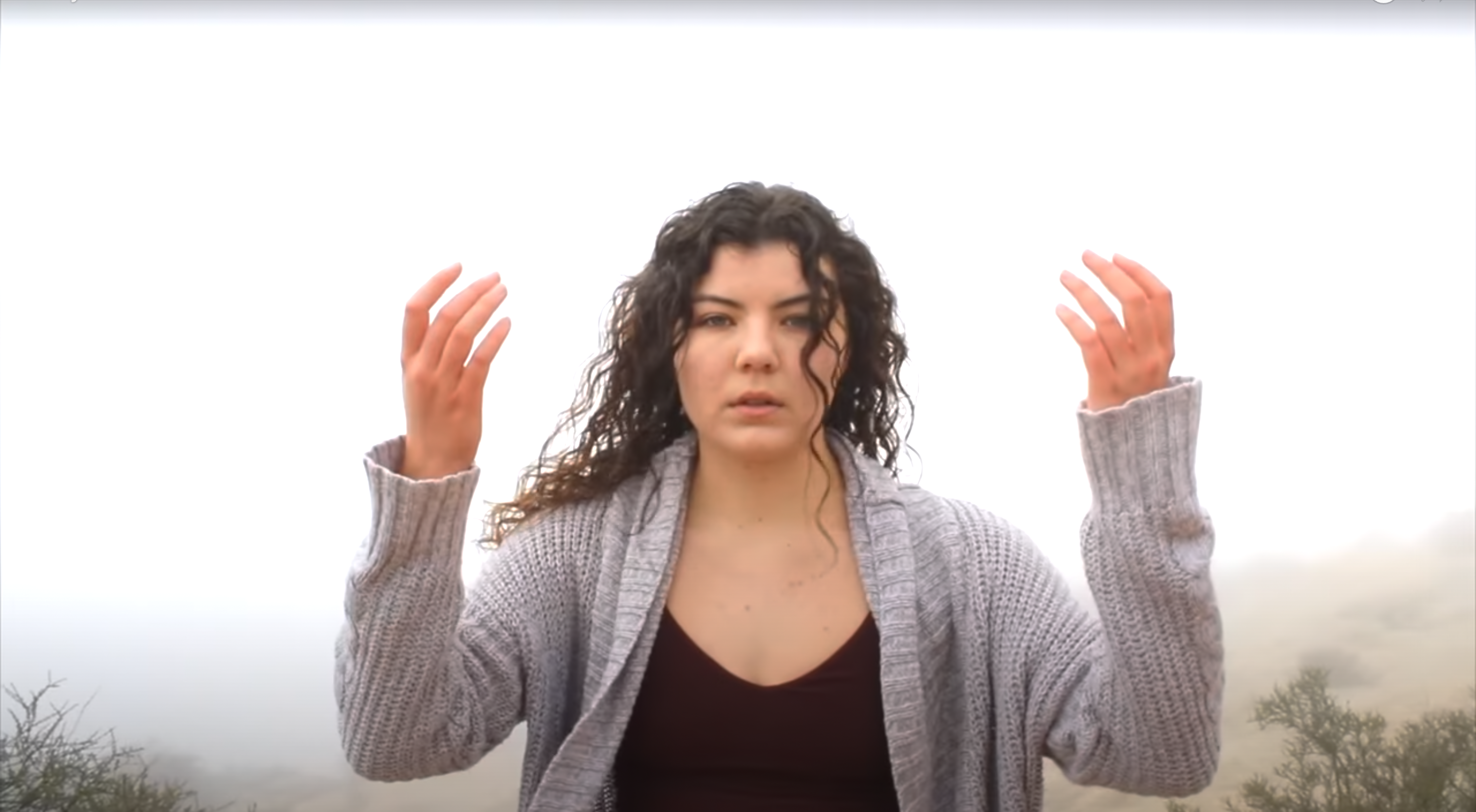 A female dancer faces the camera with her hands raised